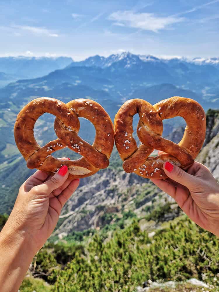 Dos chicas sujetando dos pretzels con las montanas de Salzburgo fondo