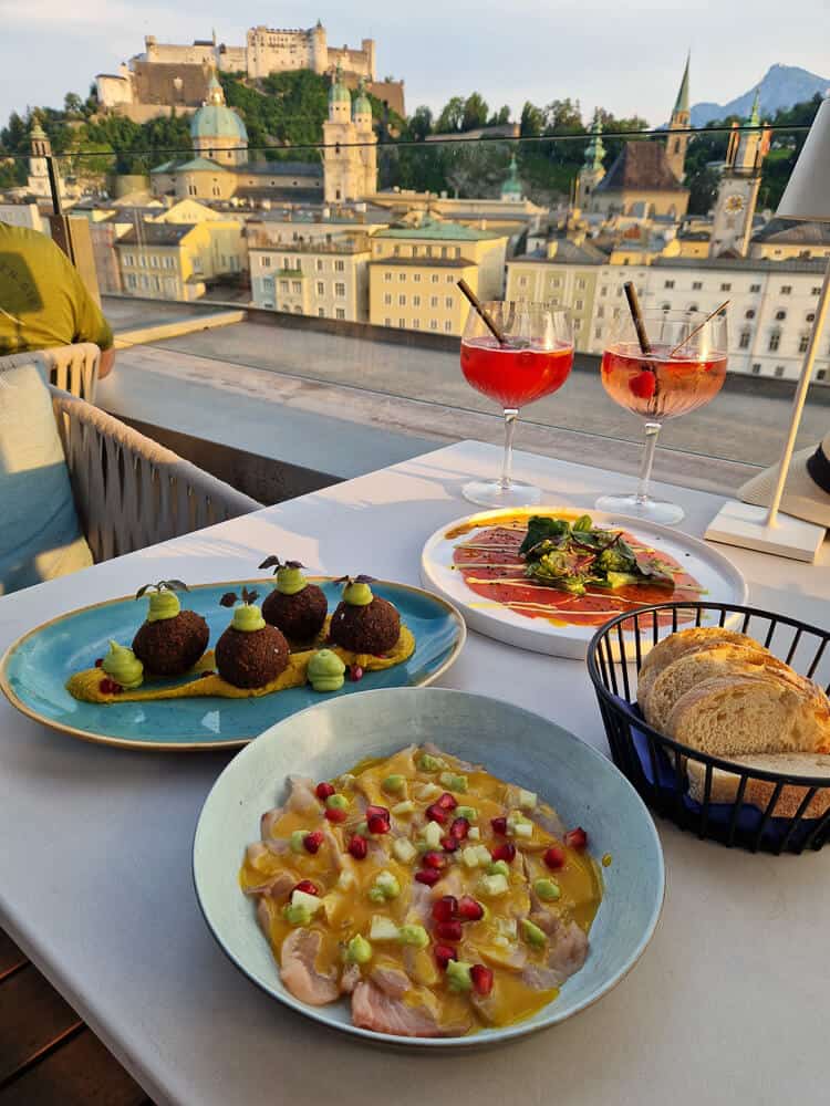 Platos de comida y cocktails en la terraza Steinterrasse al atardecer