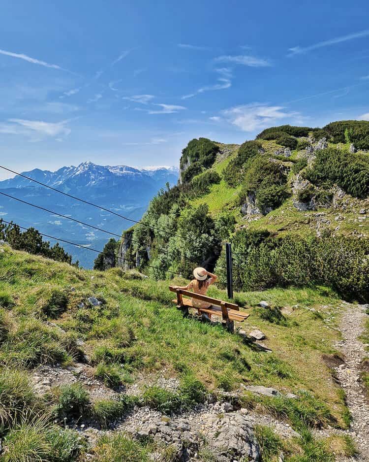 Sara sentada en un banco de madera con vistas a las montanas en Untersberg